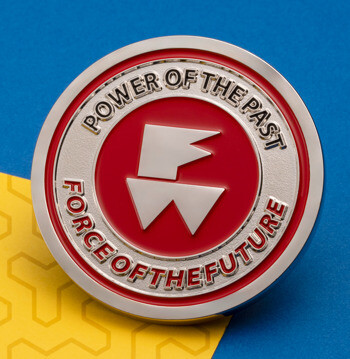 Round lapel pin featuring a red center with white FW logo and silver text border on a blue and yellow background.