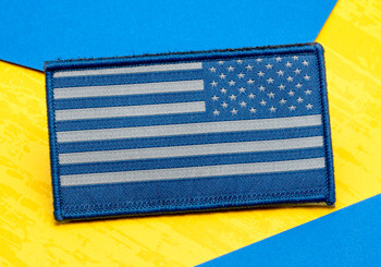 Rectangular embroidered American flag patch in blue and silver on a yellow and blue background.