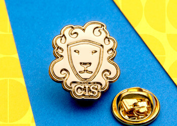 Gold-toned CIS lapel pin featuring a lion head within a shield shape and a butterfly clutch back.