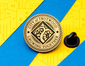 Circular gold City of Trotwood lapel pin featuring a stylized tree emblem and the text Growing Together.
