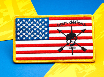 Embroidered American flag patch featuring the Nous Défions skull and crossed arrows insignia with a yellow border.