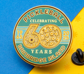 Circular lapel pin celebrating 60 years of pickleball on Bainbridge Island with gold glitter numbers and a pickleball design on a teal and green background.