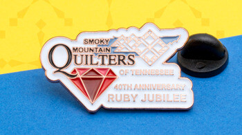 Custom enamel lapel pin for Smoky Mountain Quilters of Tennessee 40th Anniversary Ruby Jubilee featuring a red diamond and white quilt pattern.